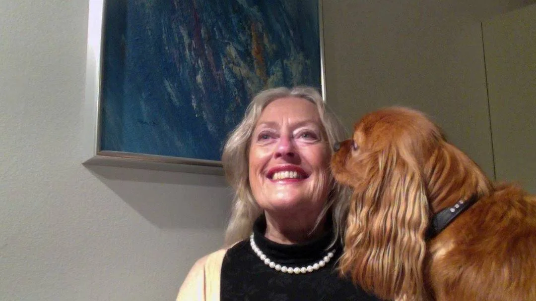 En kvinne smiler mens en rødbrun hund slikker henne i ansiktet.