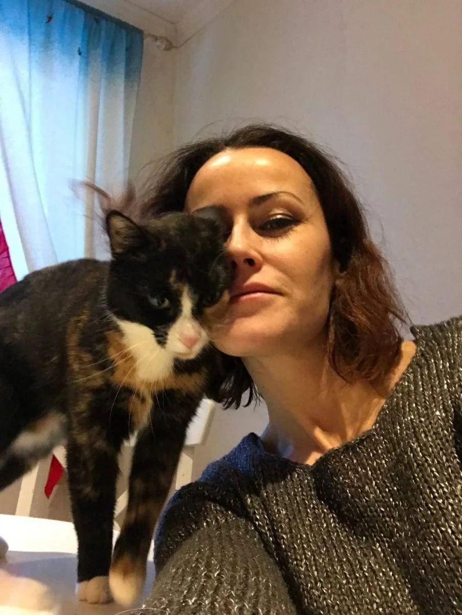 En kvinne holder ansiktet inntil en trefarget katt.