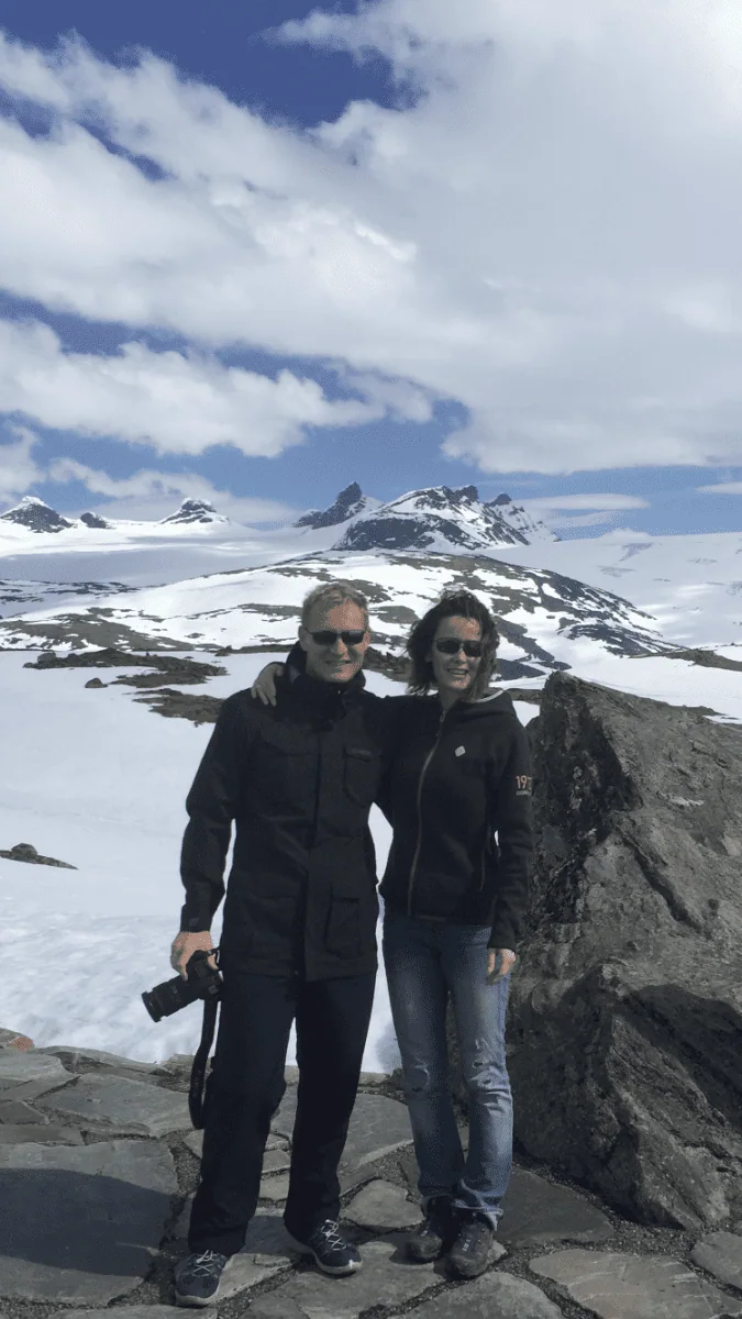 To personer står sammen i et fjellandskap med snø.