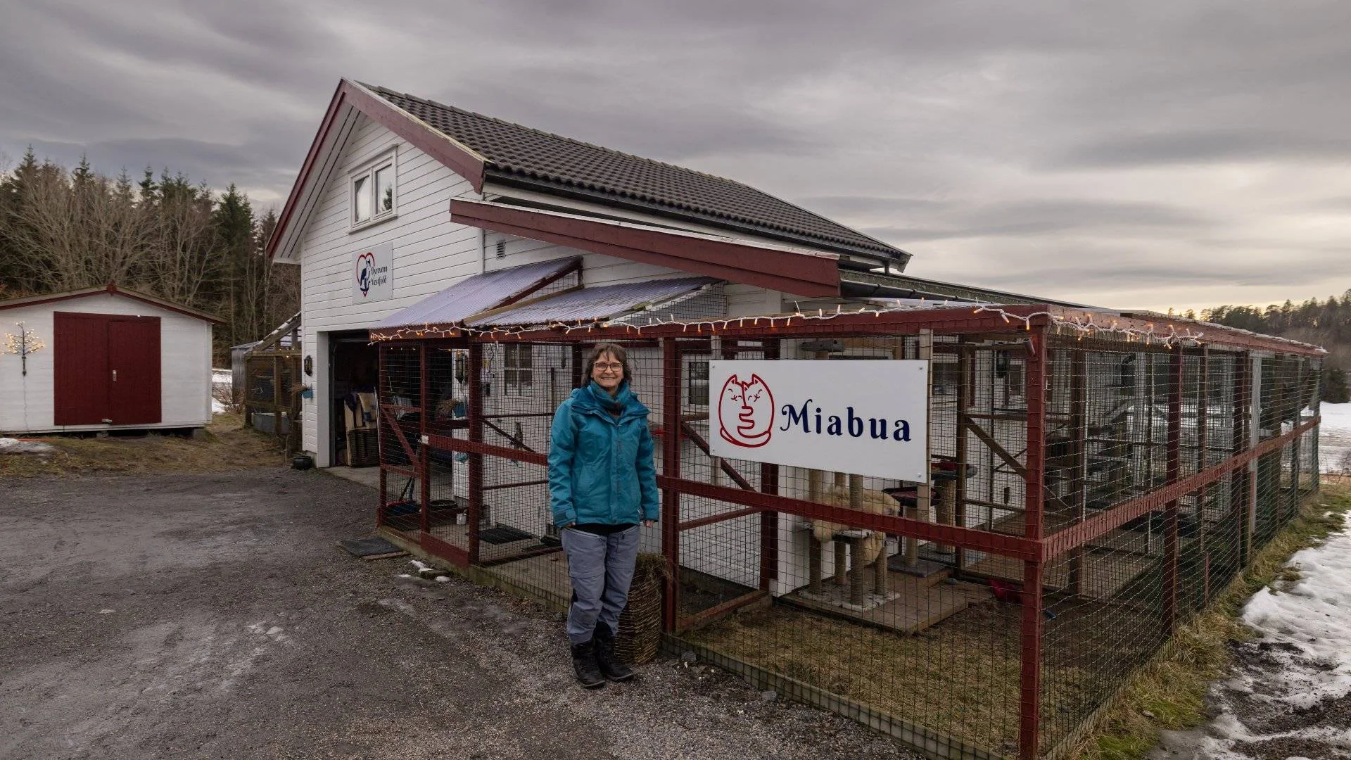 En kvinne står utenfor en bygning med kattegård og skiltet «Miabua».
