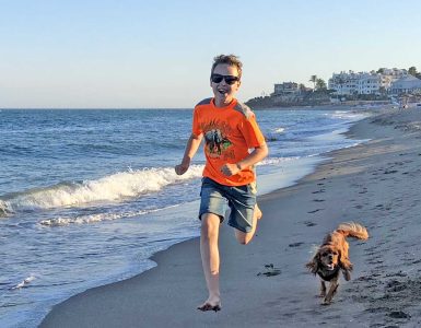 Glede - Dyr og folk Gutt og hund som løper i på stranden.