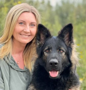 Christine Olsen sitter ute sammen med en hund.