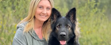 Christine Olsen sitter ute sammen med en hund.